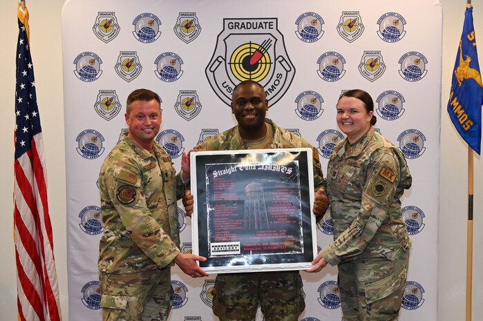 Three people posing with plaque