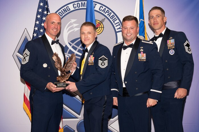 Four people posing with award
