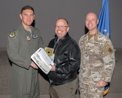 U.S. Air Force Col. Ethan Sabin, left, 57th Wing deputy commander, and Chief Master Sgt. Jason K. Trickey, right, 57th Wing command chief, present Jack Slade, an adversary network technician lead assigned to the 57th Information Aggressor Squadron, with the Civilian Category III of the Quarter award at Nellis Air Force Base, Nevada, Nov. 20, 2024.