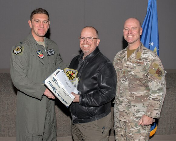 U.S. Air Force Col. Ethan Sabin, left, 57th Wing deputy commander, and Chief Master Sgt. Jason K. Trickey, right, 57th Wing command chief, present Jack Slade, an adversary network technician lead assigned to the 57th Information Aggressor Squadron, with the Civilian Category III of the Quarter award at Nellis Air Force Base, Nevada, Nov. 20, 2024.