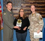 U.S. Air Force Col. Ethan Sabin, left, 57th Wing deputy commander, and Chief Master Sgt. Jason K. Trickey, right, 57th Wing command chief, present Jenny Garcia, a unit program coordinator assigned to the 757th Aircraft Maintenance Squadron with the Civilian Category I of the Quarter award at Nellis Air Force Base, Nevada, Nov. 20, 2024.