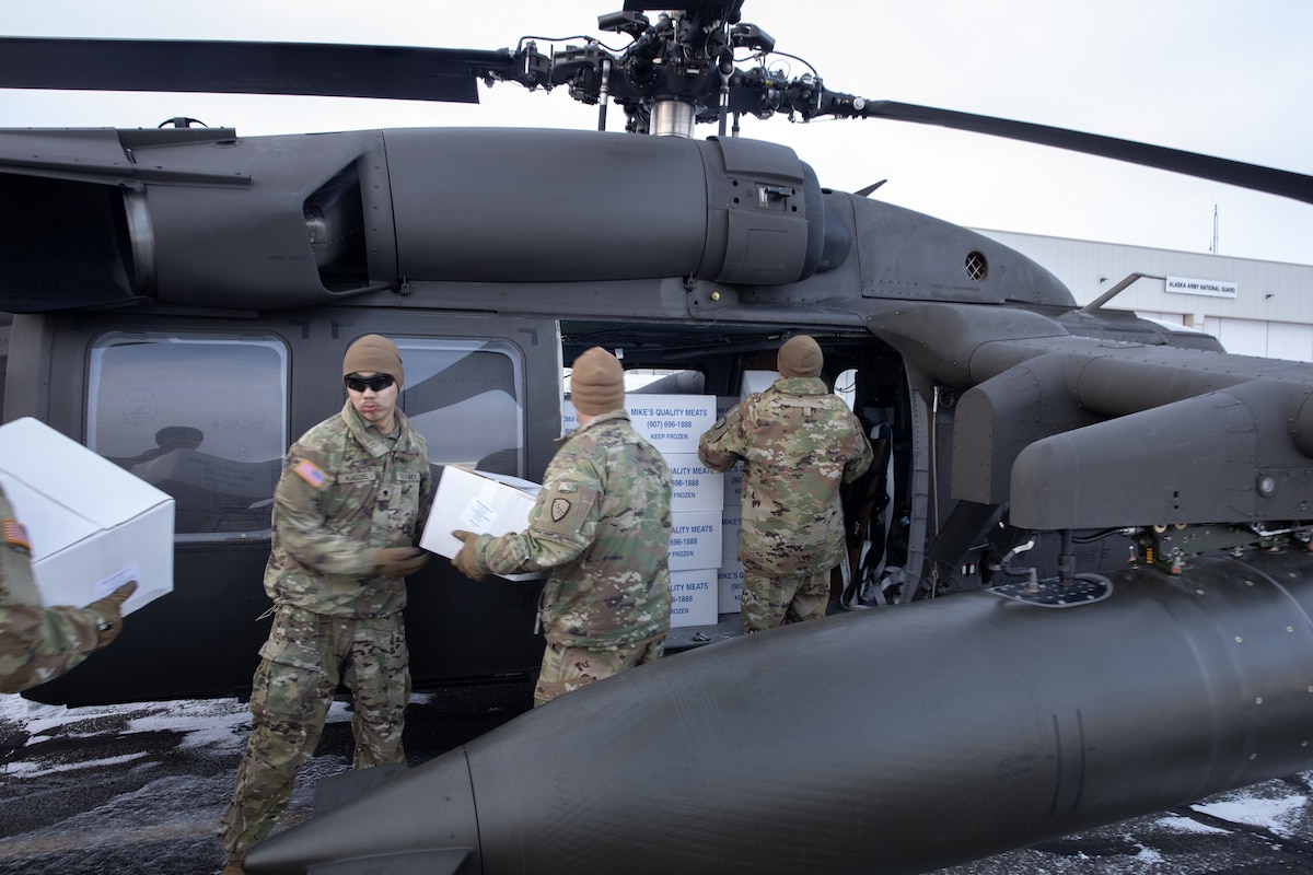 Alaska Army National Guardsmen from the 207th Aviation Troop Command and Bison Company, 1st Battalion, 297th Infantry Regiment, load frozen meat for transport via UH-60L Black Hawk helicopter during an Innovative Readiness Training mission at the AKARNG hangar in Bethel, Alaska, Nov. 18, 2024. Two years ago, the community of Toksook Bay, whose population is almost entirely members of the Alaska Native Nunakauyarmiut Tribe living a subsistence lifestyle, lost thousands of pounds of meat that spoiled due to extended power outages caused by Typhoon Merbok flooding.