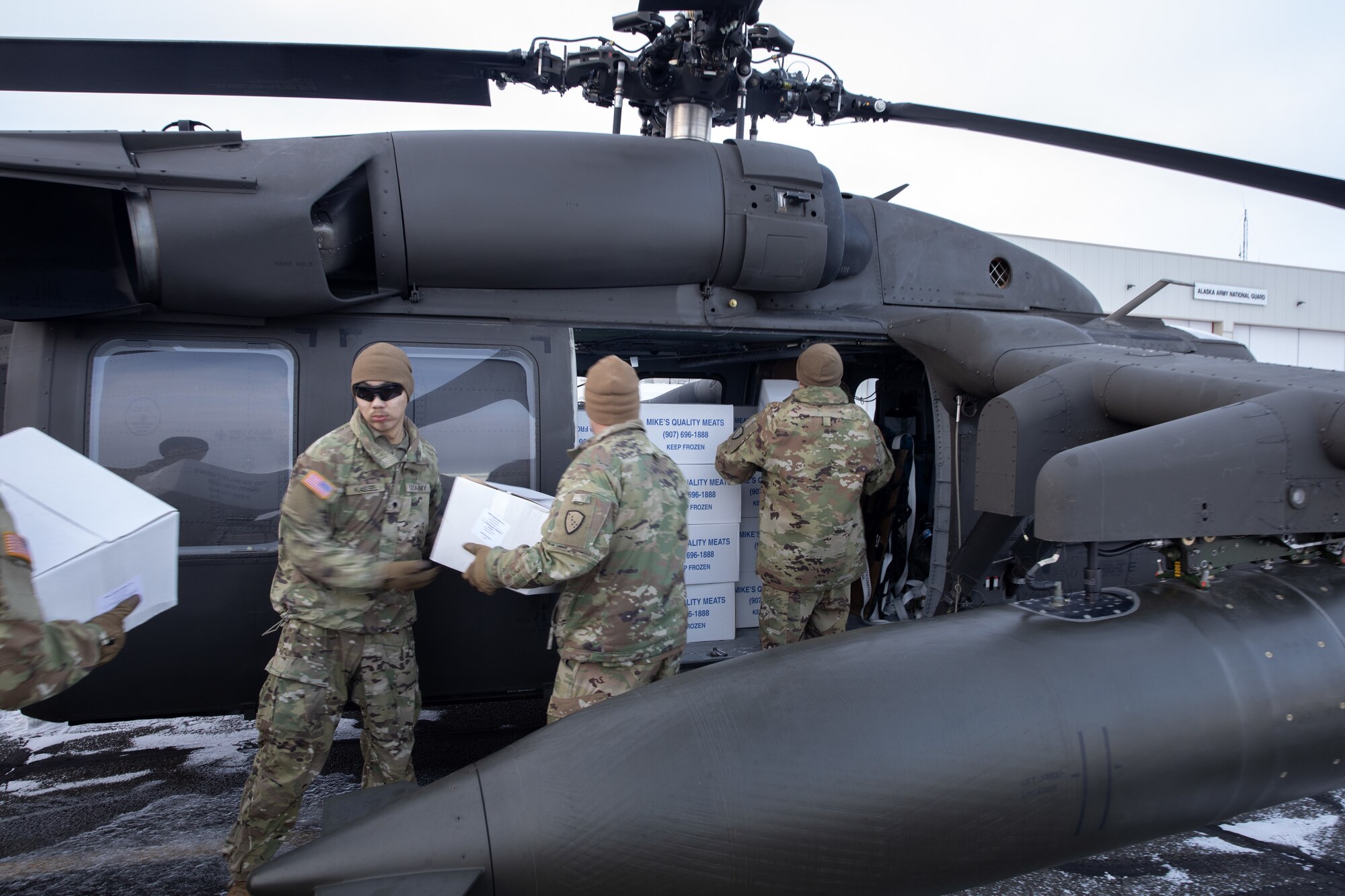 Alaska Army National Guardsmen from the 207th Aviation Troop Command and Bison Company, 1st Battalion, 297th Infantry Regiment, load frozen meat for transport via UH-60L Black Hawk helicopter during an Innovative Readiness Training mission at the AKARNG hangar in Bethel, Alaska, Nov. 18, 2024. Two years ago, the community of Toksook Bay, whose population is almost entirely members of the Alaska Native Nunakauyarmiut Tribe living a subsistence lifestyle, lost thousands of pounds of meat that spoiled due to extended power outages caused by Typhoon Merbok flooding.