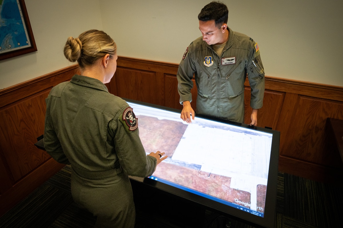 A man and woman stand around a computer table.