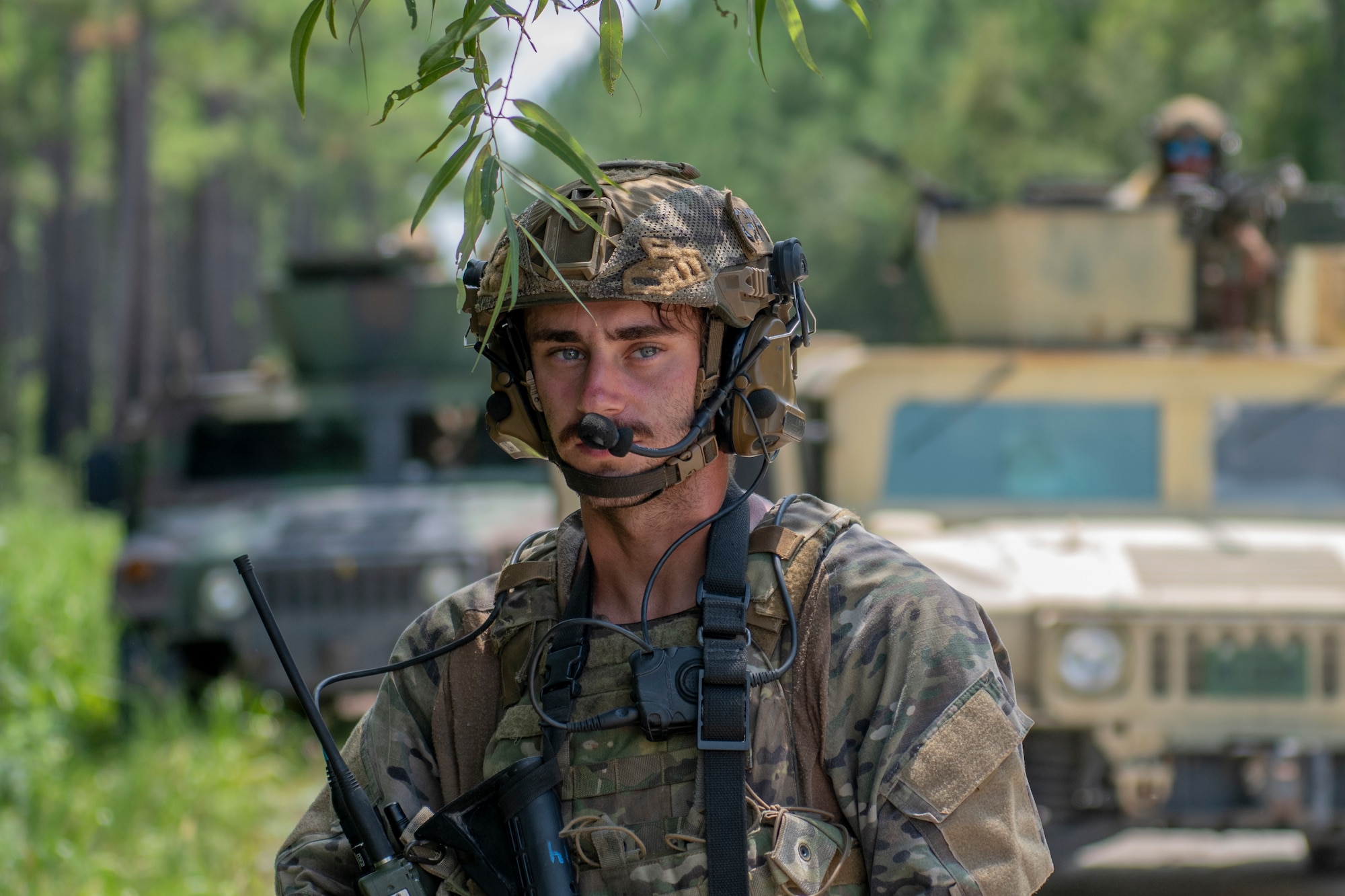 Airman kneels in front of tactical vehicles
