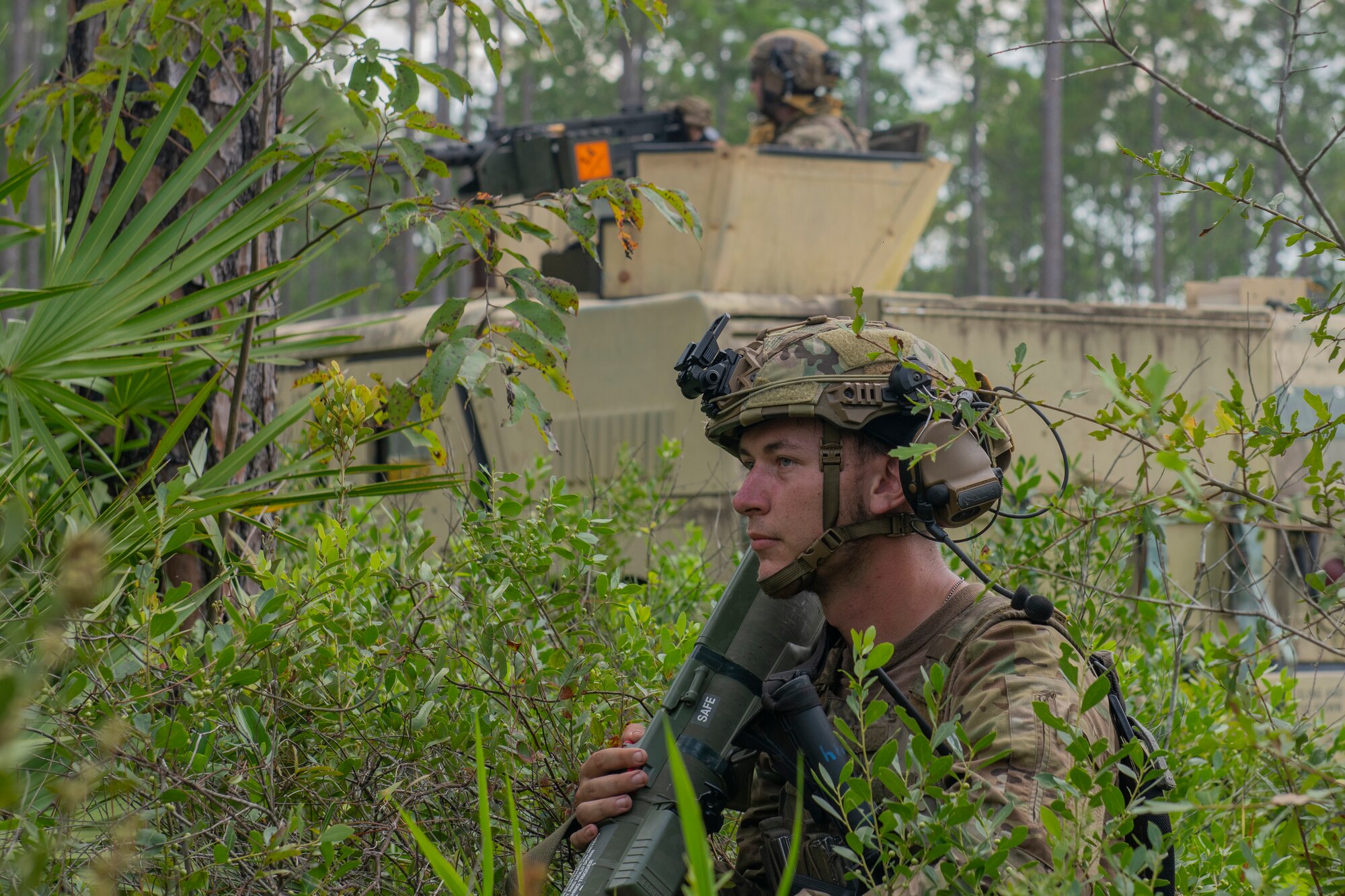 Airman kneels in front of tactical vehicle