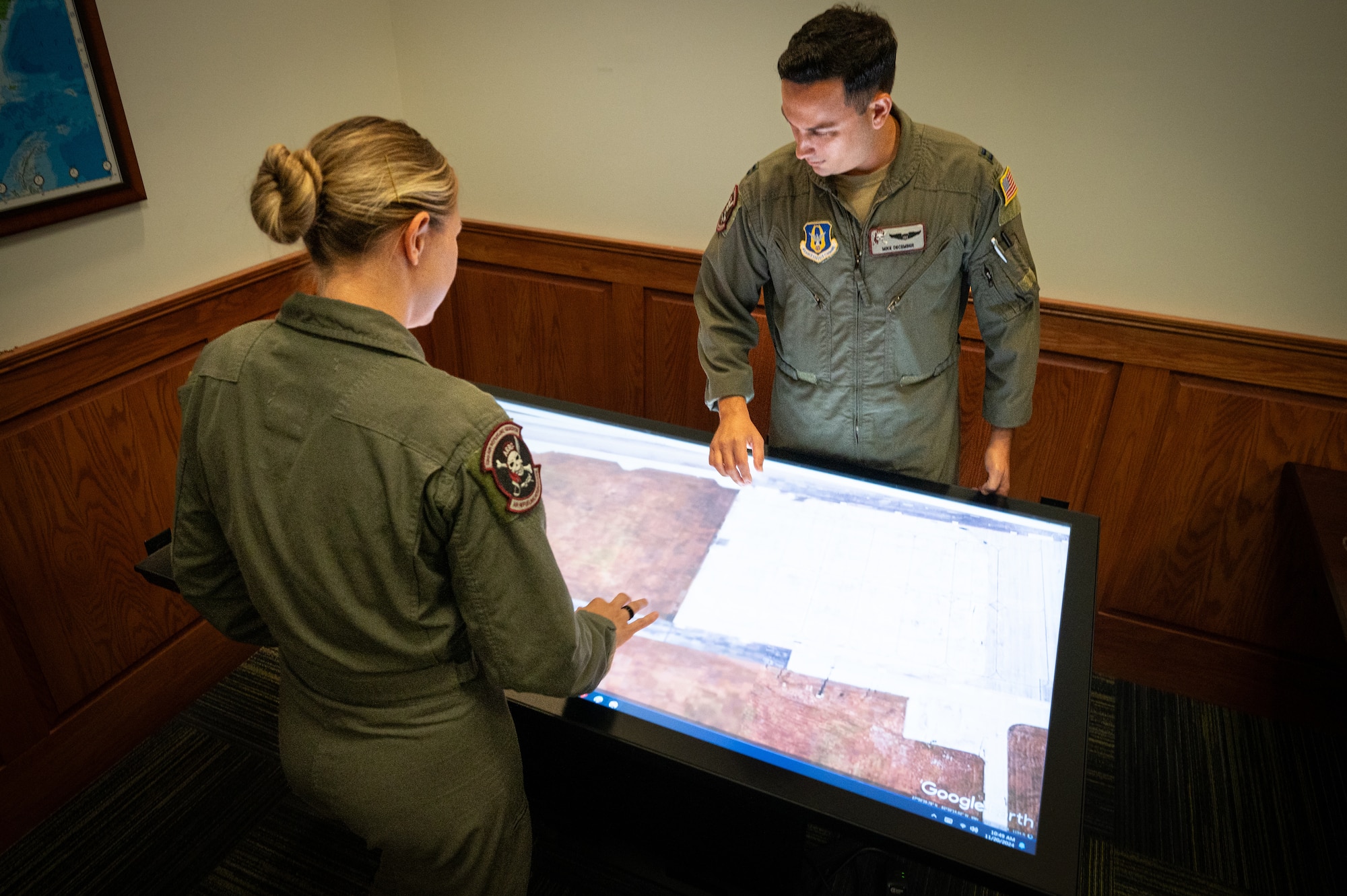 A man and woman stand around a computer table.