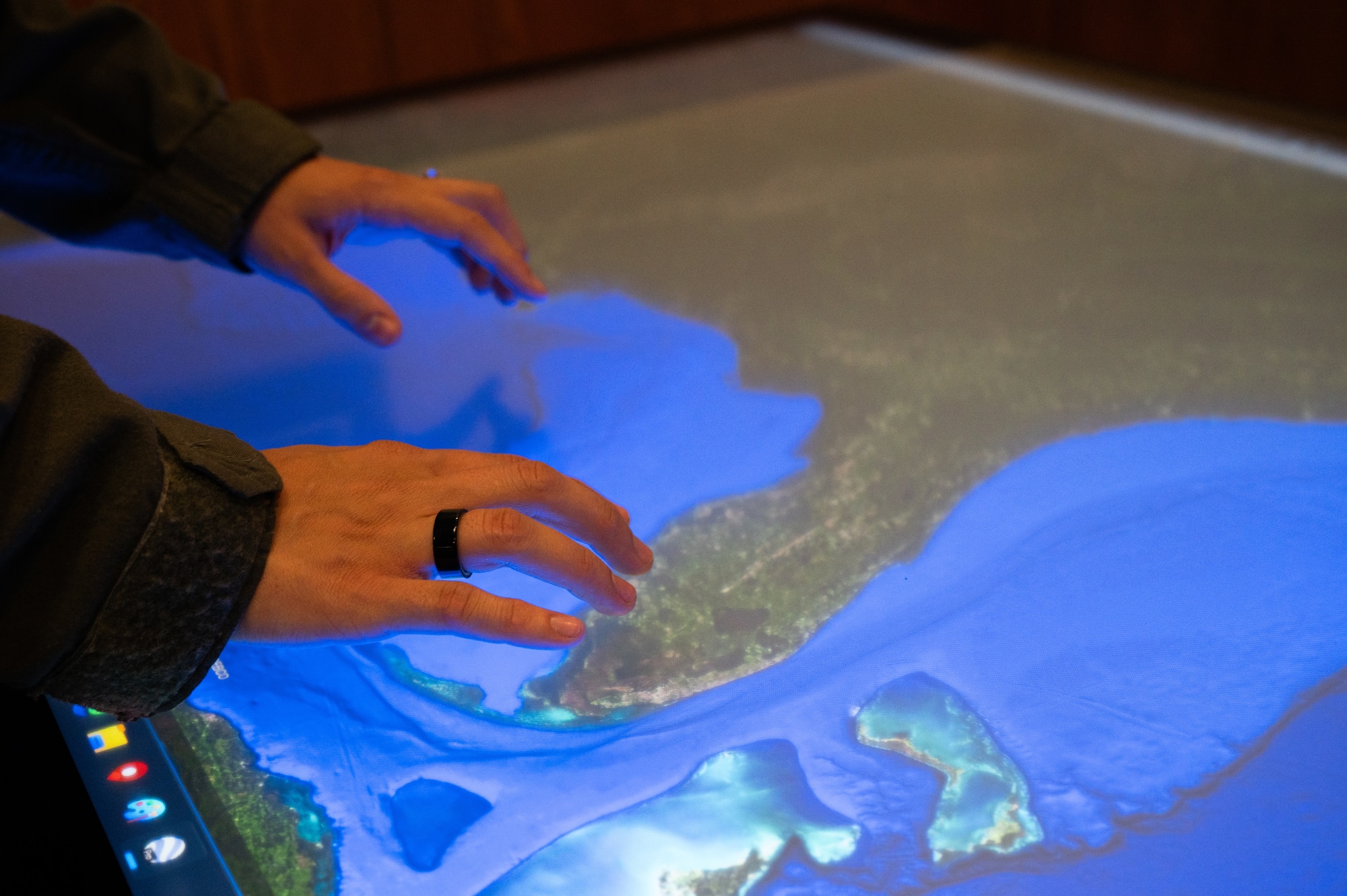 Hands on a computer screen table.