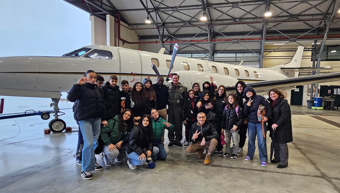 241122-N-RF791-9473 NAVAL SUPPORT ACTIVITY NAPLES (November 22, 2024) Students from Instituto Comprensivo 1 Ariosto Middle School in Arzano, Naples, pose with base personnel in front of a U.S. Naval aircraft during a base tour onboard Naval Support Activity (NSA) Naples, Italy, Nov. 22, 2024. The students also had the opportunity to gain cultural insights from U.S. Navy personnel. NSA Naples is an operational ashore base that enables U.S., allied, and partner nation forces to be where they are needed, when they are needed to ensure security and stability in Europe, Africa, and Southwest Asia. (U.S. Navy photo by Lt. j.g. Valentine K. Mulango)