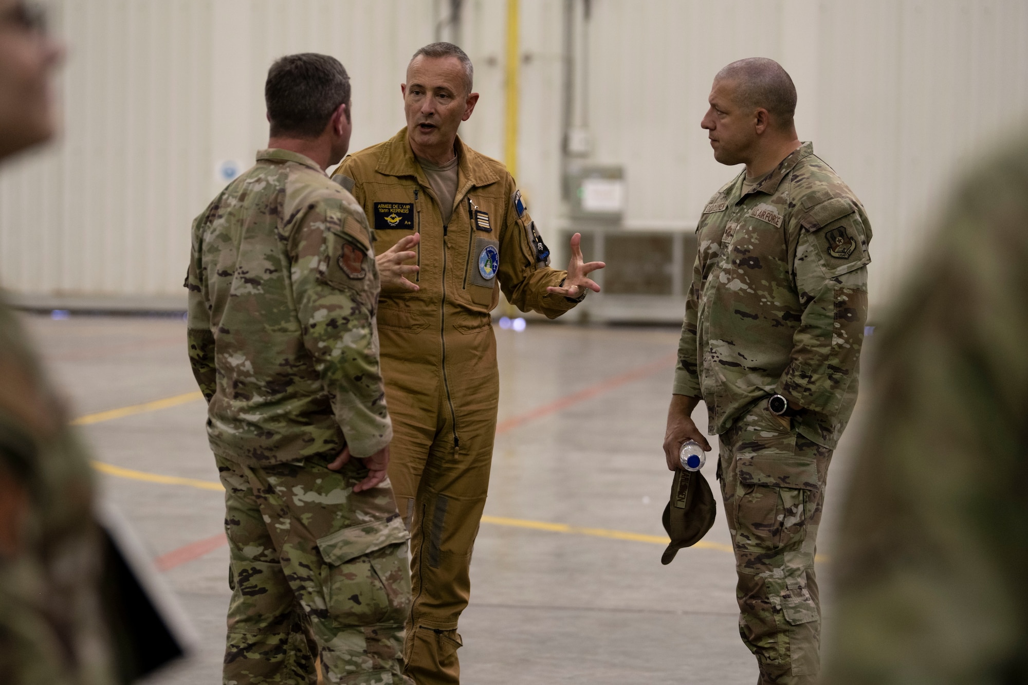 Base Aerienne 104 deputy commander (center) talks with 380th Air Expeditionary Wing leadership, Col. Paul Sheets, commander (left), and Chief Master Sgt. Joshua Skarloken, command chief (right), during an engagement.