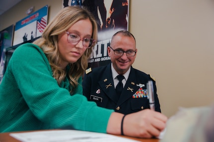 Pvt. Kristen Buck (left) enlists in the Oklahoma Army National Guard as a religious affairs specialist, Oct. 15, 2024. Kristen continues her family's legacy by following in her father's footsteps, Maj. Christopher Buck (right), who has been a member of the Oklahoma Army National Guard for the past 25 years. (Oklahoma National Guard photo by Staff Sgt. Reece Heck)