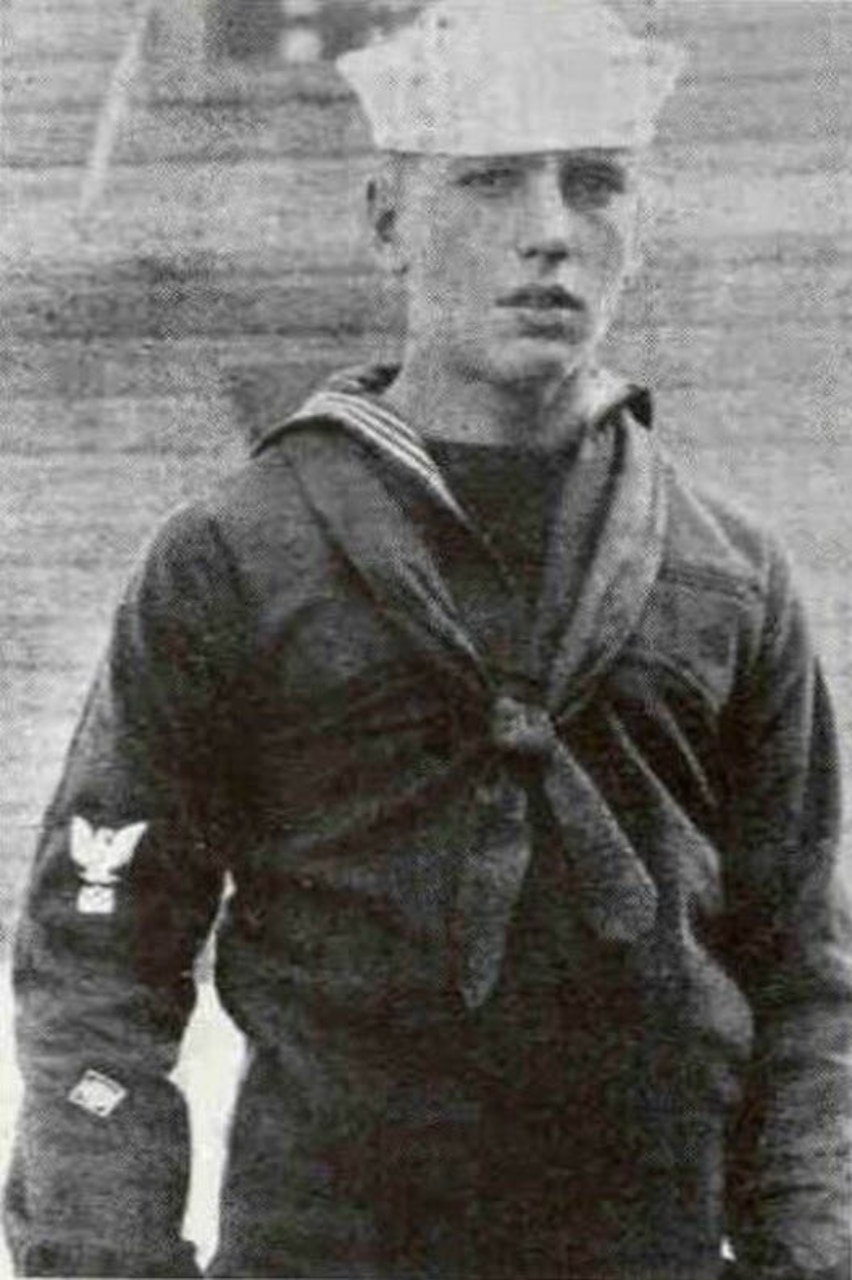 A sailor in uniform poses for a photo.