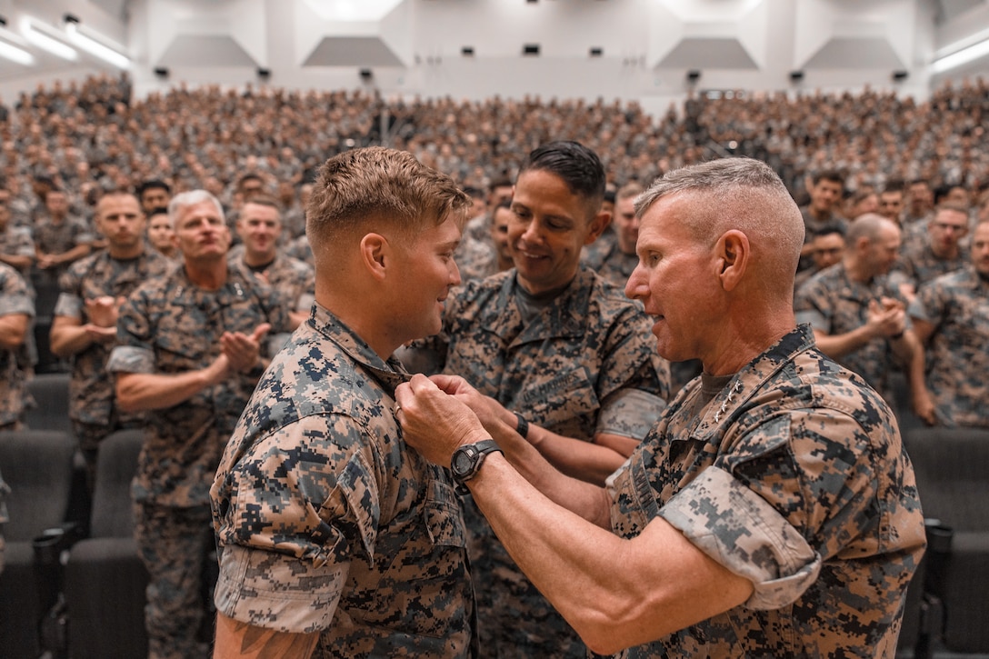 The 39th Commandant of the Marine Corps, Gen. Eric M. Smith, and the 20th Sergeant Major of the Marine Corps, Sgt. Maj. Carlos A. Ruiz pin Nicholas Figueroa, a reconnaissance Marine with 3rd Reconnaissance Battalion, III Marine Expeditionary Force, to the rank of corporal at Marine Corps Base Camp Schwab, Okinawa, Japan, Sept. 6, 2024. General Smith visited Camp Schwab to receive updates on their training, modernization efforts, and to speak with Marines and recognize their accomplishments. (U.S. Marine Corps photo by Staff Sgt. Kelsey Dornfeld)