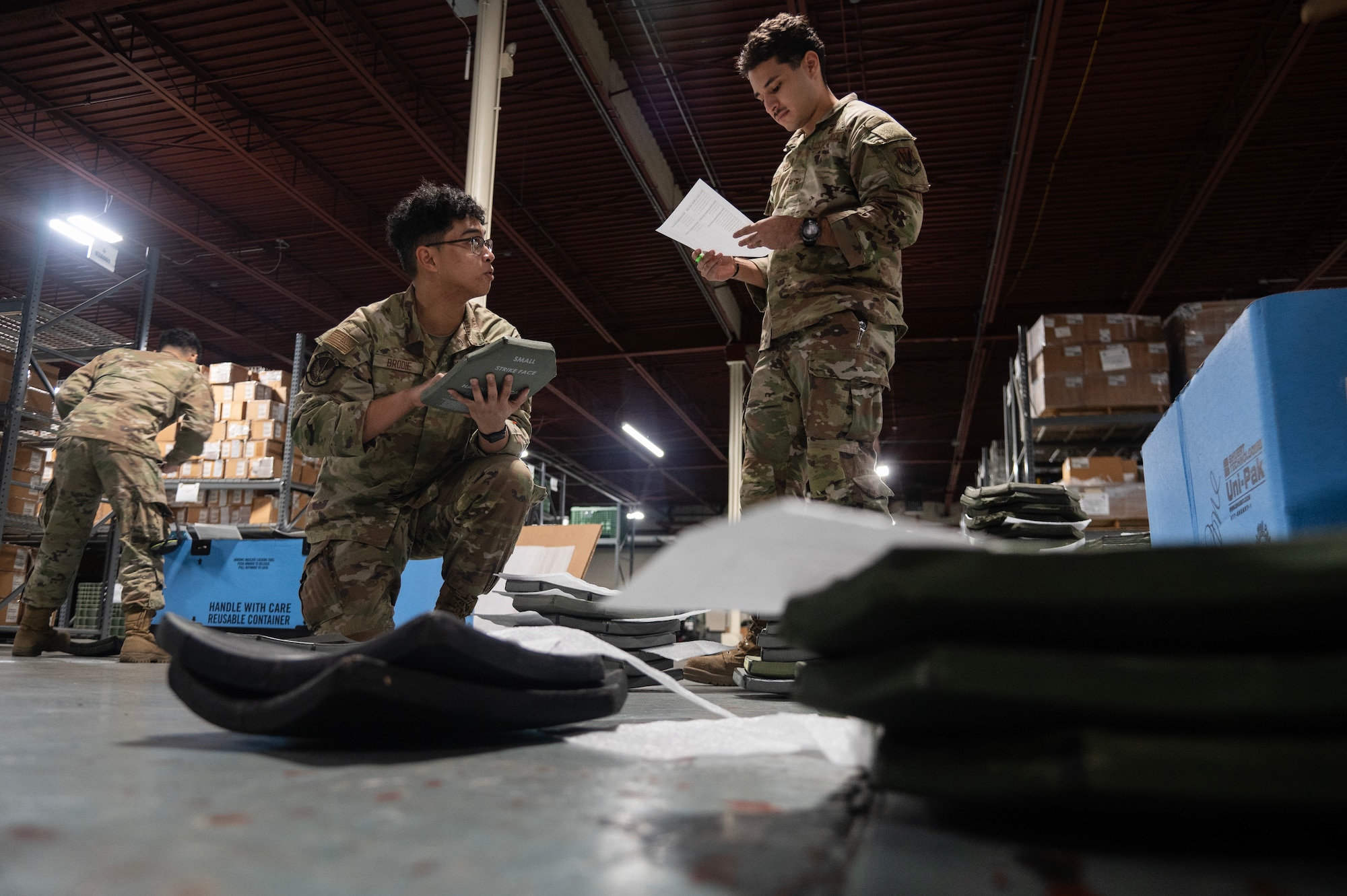 Airman John Matt Brodie, left, and Airman 1st Class Efrain Figueroa, right, 4th Logistics Readiness Squadron Individual Protective Equipment (IPE) apprentices, verify serial numbers assigned to Interceptor Body Armor plates.