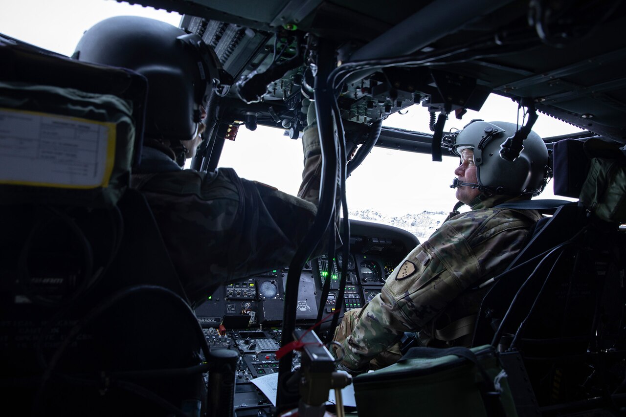 A pair of soldiers sit in the cockpit of a helicopter.