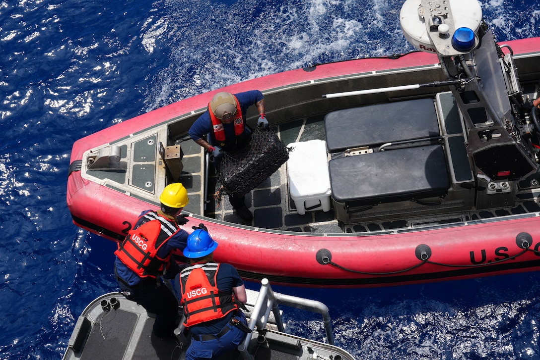 U.S. Coast Guard Petty Officer Second Class David Rind passes a bale of contraband to Petty Officer First Class Zachary Domingue and Petty Officer Third Class Aaron Stearns. Coast Guard Cutter Munro (WMSL 755) interdicted a total of ten vessels suspected of narcotics smuggling in the Eastern Pacific Ocean, resulting in the seizure of over 30,000 lbs. of cocaine worth an estimated $440 million in wholesale value. (U.S. Coast Guard photo by L.t. j.g. Grade Samika Lewis)