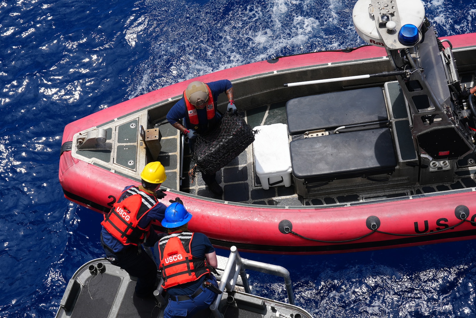 U.S. Coast Guard Petty Officer Second Class David Rind passes a bale of contraband to Petty Officer First Class Zachary Domingue and Petty Officer Third Class Aaron Stearns. Coast Guard Cutter Munro (WMSL 755) interdicted a total of ten vessels suspected of narcotics smuggling in the Eastern Pacific Ocean, resulting in the seizure of over 30,000 lbs. of cocaine worth an estimated $440 million in wholesale value. (U.S. Coast Guard photo by L.t. j.g. Grade Samika Lewis)