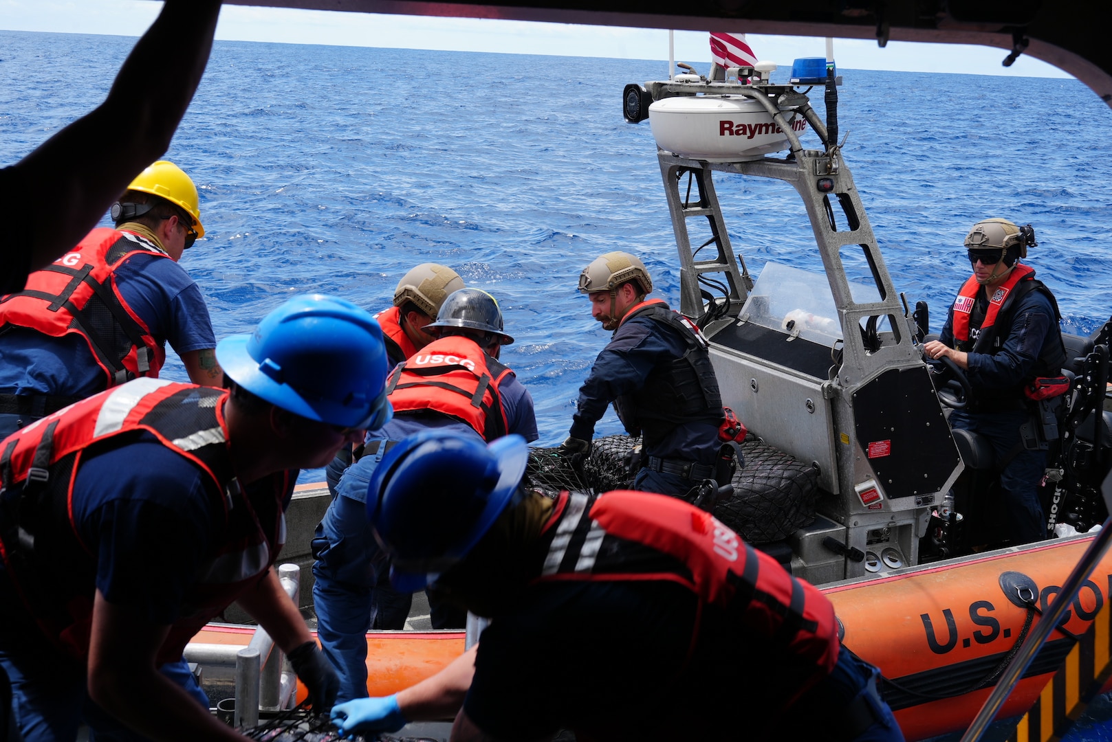 Petty Officer Second Class Jacob Weaver passes over a bale of contraband to bring onto U.S. Coast Guard Cutter Munro (WMSL 755) via the rescue station door as Petty Officer First Class Mason Knudtson maneuvers the Over-the-Horizon small boat alongside the cutter. Munro interdicted a total of 11 vessels suspected of narcotics smuggling in the Eastern Pacific Ocean, resulting in the seizure of over 30,000 lbs. of cocaine, worth an estimated $440 million in wholesale value. (U.S. Coast Guard photo by L.t. j.g. Samika Lewis)