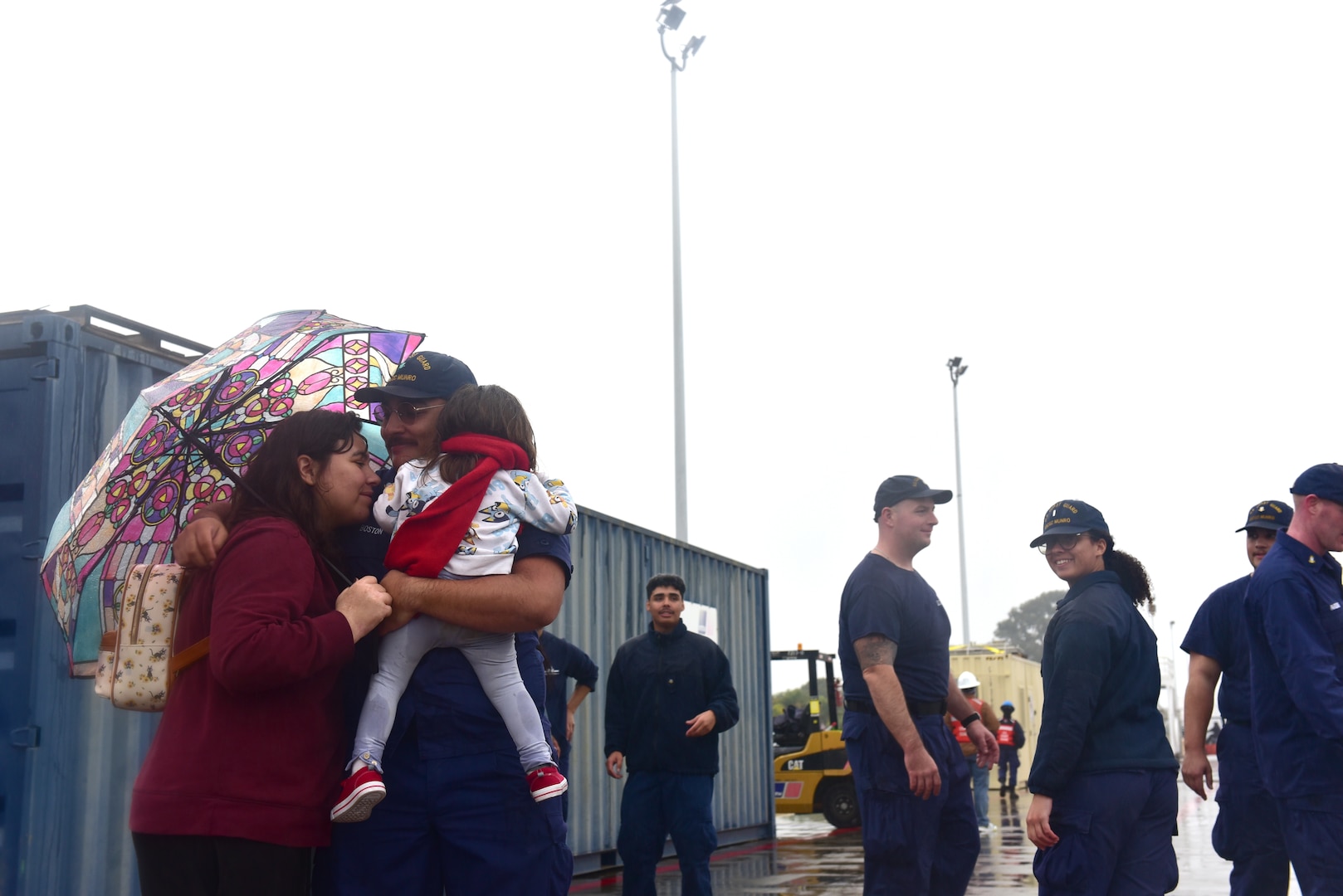 U.S. Coast Guard Cutter Munro (WMSL 755) crew member embraces his wife and daughter after the cutter returned to its homeport at Base Alameda, California, Nov. 25, 2024, following a two-month Eastern Pacific patrol. Munro is one of four Legend-class national security cutters homeported on Base Alameda. (U.S. Coast Guard photo by Petty Officer 3rd Class Danish Khan)