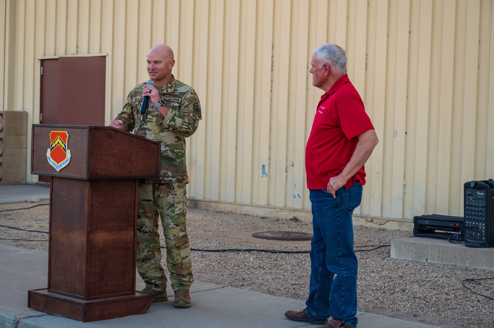 U.S. Air Force Brig. Gen. Dave Berkland, 56th Fighter Wing commander, congratulates Retired Col. Robert McCutchen, Lockheed Martin networked training center operations manager, during a farewell ceremony for the last F-16 Fighting Falcon simulators, Nov. 22, 2024, at Luke Air Force Base, Arizona.