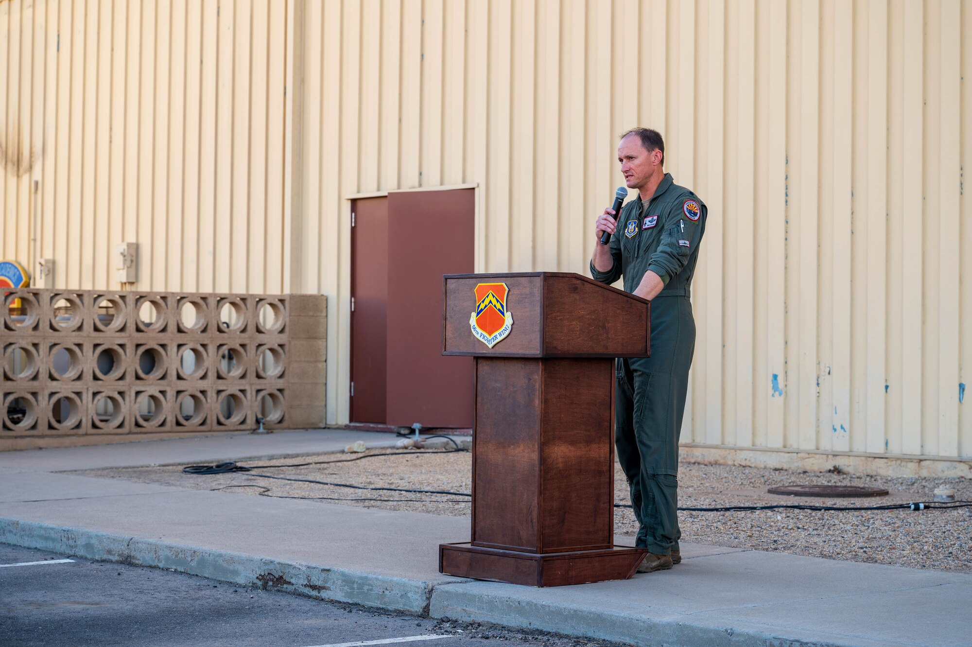 U.S. Air Force Lt. Col. Donald Huggins, 69th Fighter Squadron instructor pilot, welcomes attendees to a farewell ceremony for the last F-16 Fighting Falcon simulators, Nov. 22, 2024, at Luke Air Force Base, Arizona.