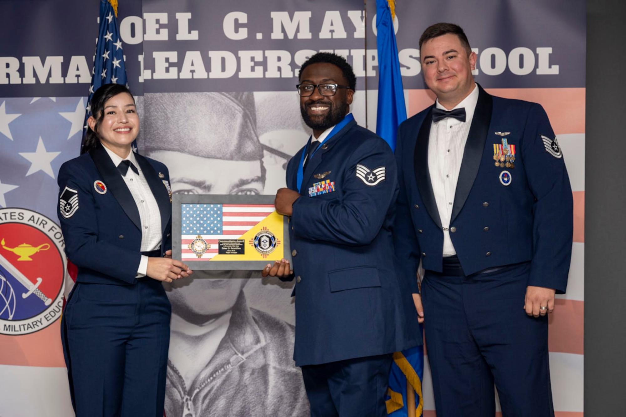 U.S. Air Force Staff Sgt. Peter Saintilien, center, Airman Leadership Graduate, accepts the Commandant’s Award from U.S. Air Force Master Sgt. Cecilia Ayon, left, and U.S. Air Force Tech. Sgt. Devin Milburn, during the graduation of Joel C. Mayo Class 25-A at Holloman Air Force Base, New Mexico, Nov. 21, 2024. The Commandant’s award is selected by the ALS commandant and is presented to the student who best demonstrates the characteristics of an effective leader. (U.S. Air Force photo by Airman 1st Class Michelle Ferrari)