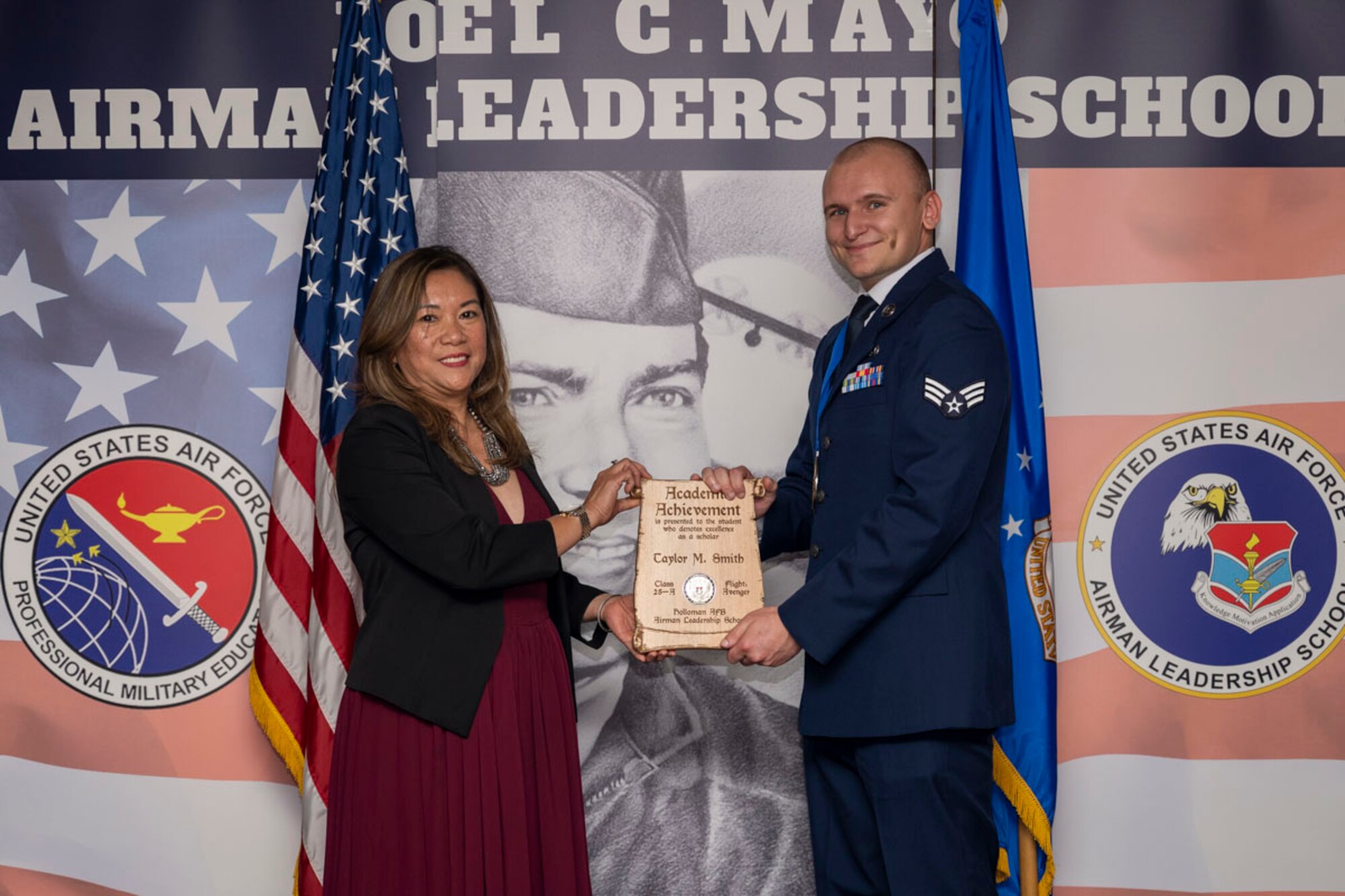 U.S. Air Force Senior Airman Taylor Smith, right, Airman Leadership Graduate, accepts the Academic Achievement Award from Mrs. Lany Cooper, during the graduation of Joel C. Mayo ALS Class 25-A at Holloman Air Force Base, New Mexico, Nov. 21, 2024. The academic award is presented to the student with the highest overall average on all academic evaluations and demonstrations of leadership. (U.S. Air Force photo by Airman 1st Class Michelle Ferrari)