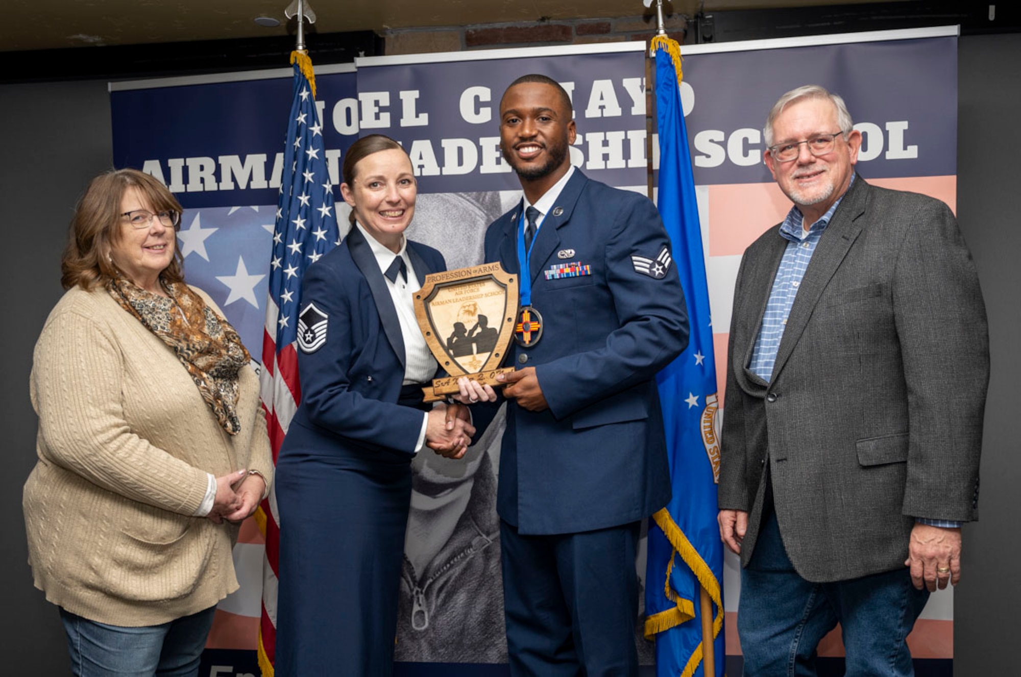 U.S. Air Force Senior Airman Xavier O’Neal accepts the Profession of Arms Award from Craig and Sue Danekas during the graduation of Joel C. Mayo ALS Class 25-A at Holloman Air Force Base, New Mexico, Nov. 21, 2024. The Profession of Arms Award recognizes the student who most embodies the profession of arms, which is demonstrated with a comprehensive understanding of the warrior ethos, oath of enlistment, and the airman’s creed. (U.S. Air Force photo by Airman 1st Class Michelle Ferrari)