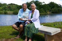 Bruce Keaulani and Kehaulani Lum, known as Uncle Bruce and Aunty Kehau, are featured to highlight the book, Ho'oponopono is Harmony, a children's book published in 2024 and written by Thao "Kale'a" Le in collaboration with Uncle Bruce, which was inspired by Loko I'a Pa'aiau, the ancient fishpond next to McGrew Point Navy Housing where they sit with a copy of the book. The story is about a boy who helps restore a 400-year old fishpond and, in the process, finds healing and harmony within himself. On Nov. 18, 2023, the Navy along with leaders from Living Life Source Foundation, Al'i Pauahi Hawaiian Civic Club, Na Lima No'eau and affiliated native Hawaiian organizations signed a memorandum of understanding (MOU) to solidify and continue efforts to preserve, restore, and maintain Loko I'a Pa'aiau. The MOU has no end date which means the partnership will provide lasting benefits to the community. (U.S. Navy photo by Kyler Hood)