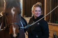 Photo of U.S. Air Force Senior Airman Analie Choquette, a Transportation Movement Operations Specialist assigned to the 158th Fighter Wing, standing next to her horse, Prada, at a barn in Orange, Vermont, Nov. 17, 2024.