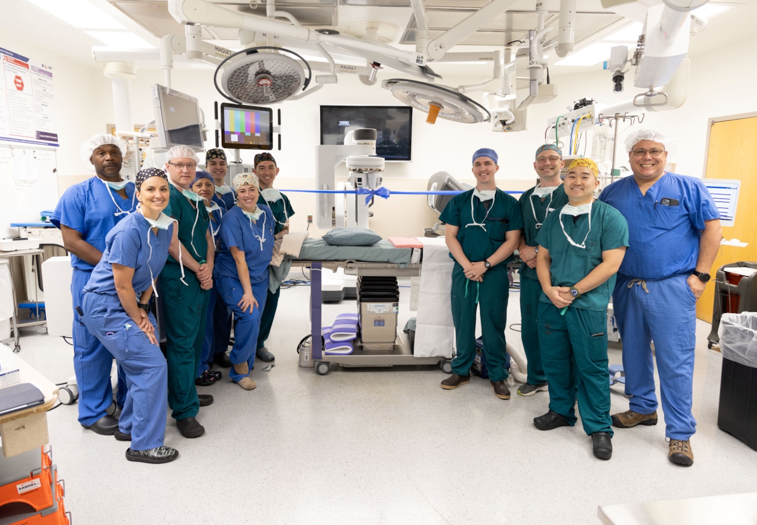 Surgeons wearing scrubs stand around machine in operating room.