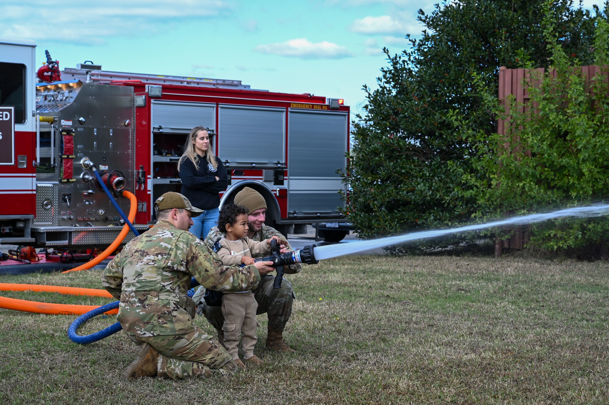 Airmen help a child fire water out of a hose. (U.S. Air Force photo by Senior Airman Abigayl Salyer)