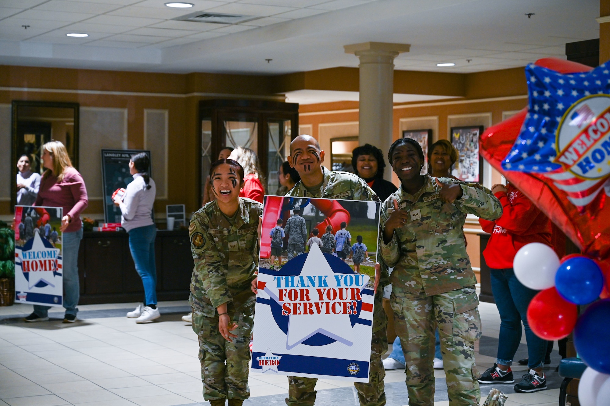Airmen hold welcome sign indoors. (U.S. Air Force photo by Senior Airman Abigayl Salyer)