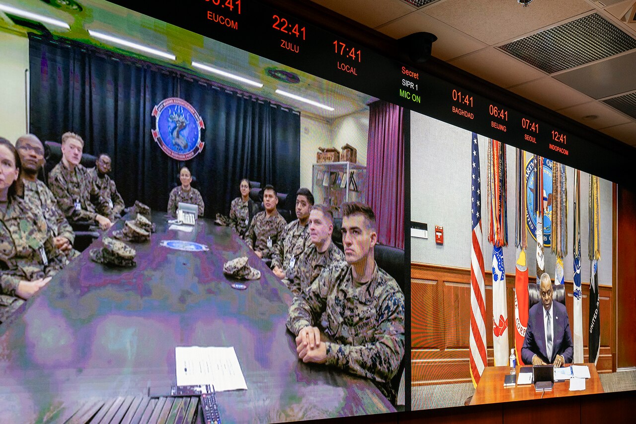 A split monitor screen - one side a group of service members the other side the secretary of defense.