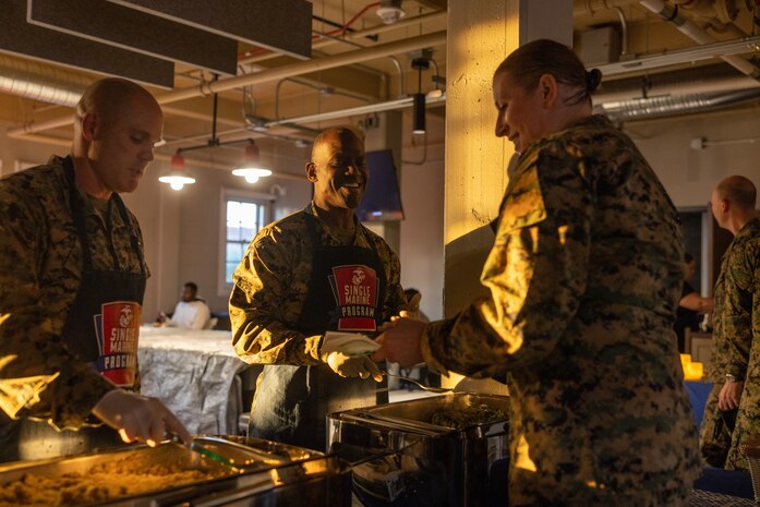 U.S. Marine Corps Sgt. Maj. Oranjel Leavy, center, sergeant major of Marine Corps Recruit Depot San Diego and the Western Recruiting Region, and Sgt. Maj. Thomas Bachman, left, sergeant major of Headquarters and Service Battalion, serve food to Staff Sgt. Melissa Karnath, a communication strategy and operations chief with Headquarters Company, at a friendsgiving event coordinated by the Depot Single Marine Program at Marine Corps Recruit Depot San Diego, California, Nov. 20, 2024. Friendsgiving is part of Spiritual Fitness Month, The Depot celebrated Spiritual Fitness Month, a program implemented to bring inner strength from higher purpose, with a friendsgiving event. MCRDSD is the first Marine Corps base to implement the Spiritual Fitness Month program. (U.S. Marine Corps photo by Cpl. Alexander O. Devereux)