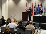 Man addresses audience in conference room