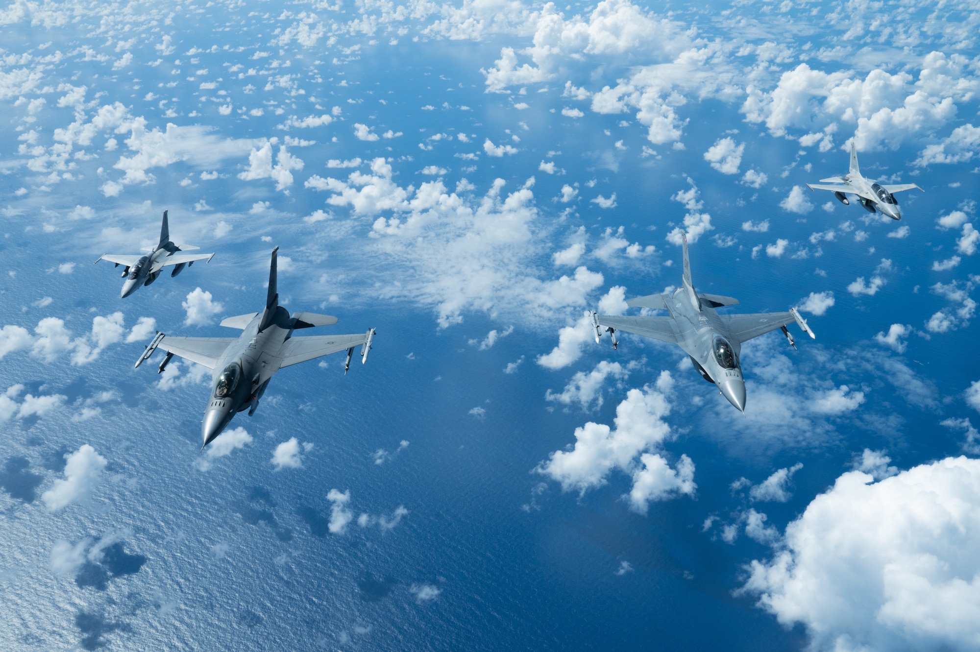 Bilateral aircraft fly in formation over the ocean.