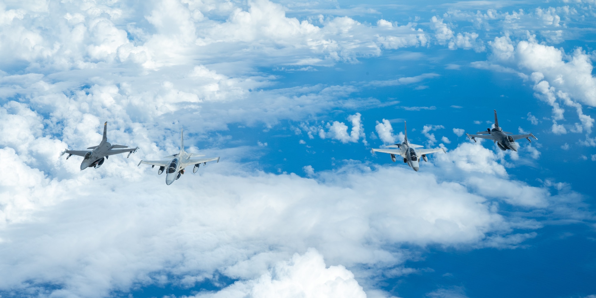 Bilateral aircraft fly in formation over the ocean.