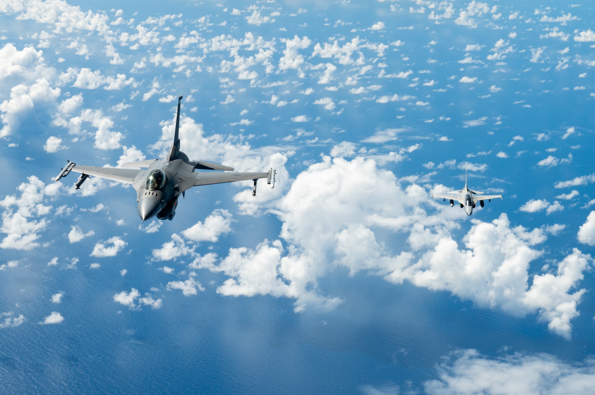 Bilateral aircraft fly in formation over the ocean.