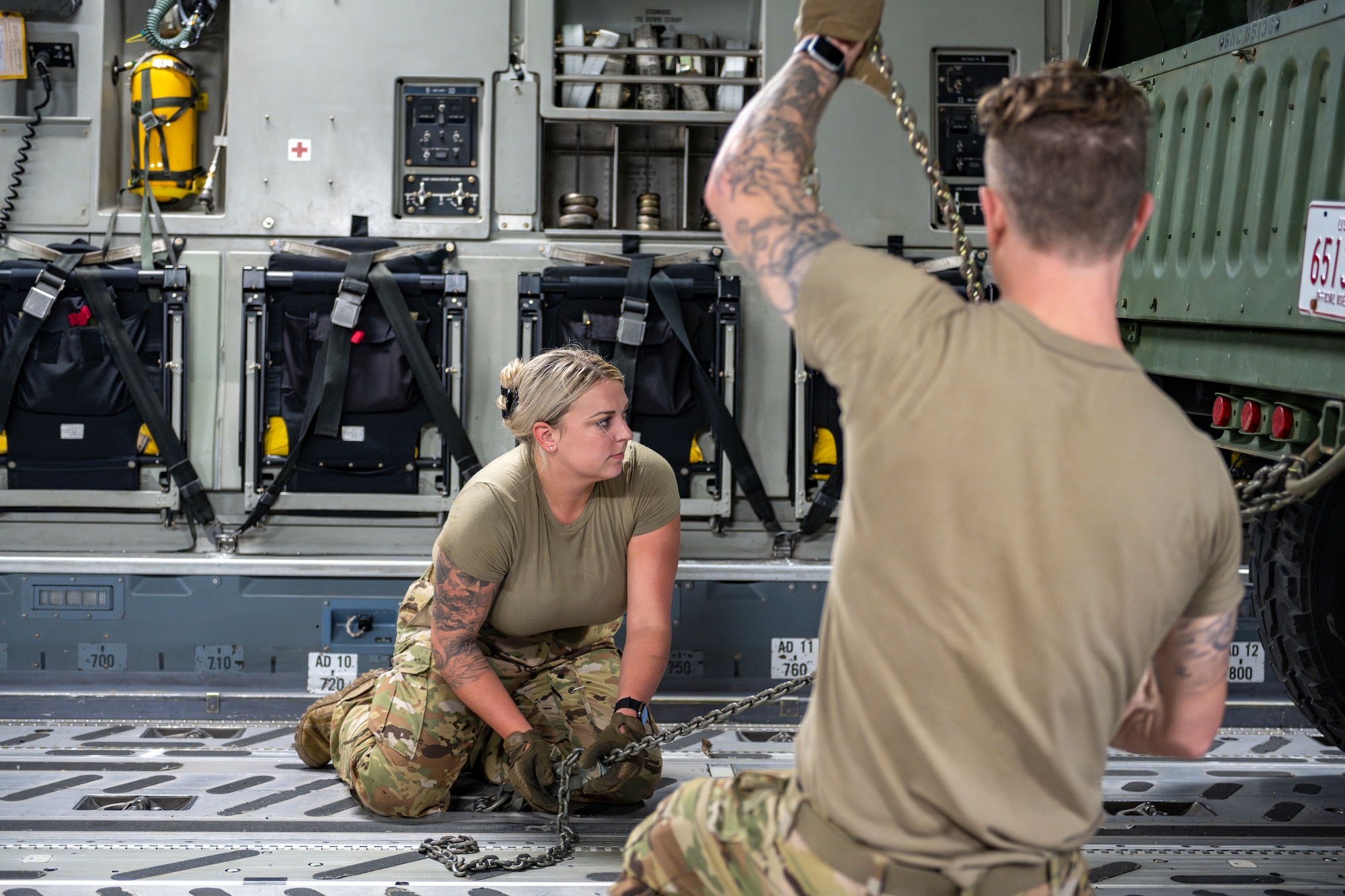Two Air Force loadmasters secure a vehicle to a C-17 Globemaster III