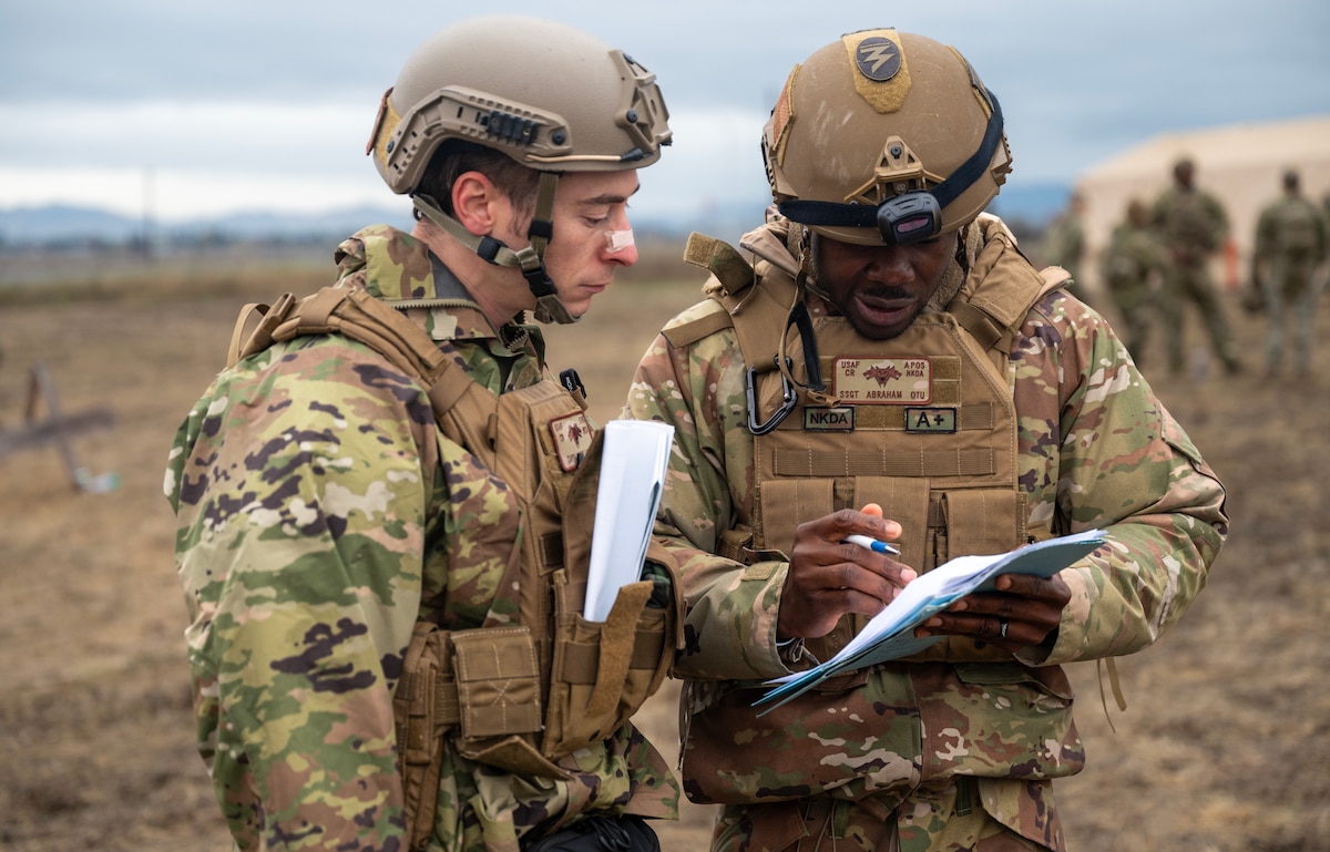 U.S. Air Force Capt. James Schackelton, left, 821st Contingency Response director of staff, and Staff Sgt. Abraham Otu, right, an 821st CRS personnel support team lead, discuss accountability during a part task trainer at the Global Readiness Deployment Center on Travis Air Force Base, California, Nov. 21, 2024.