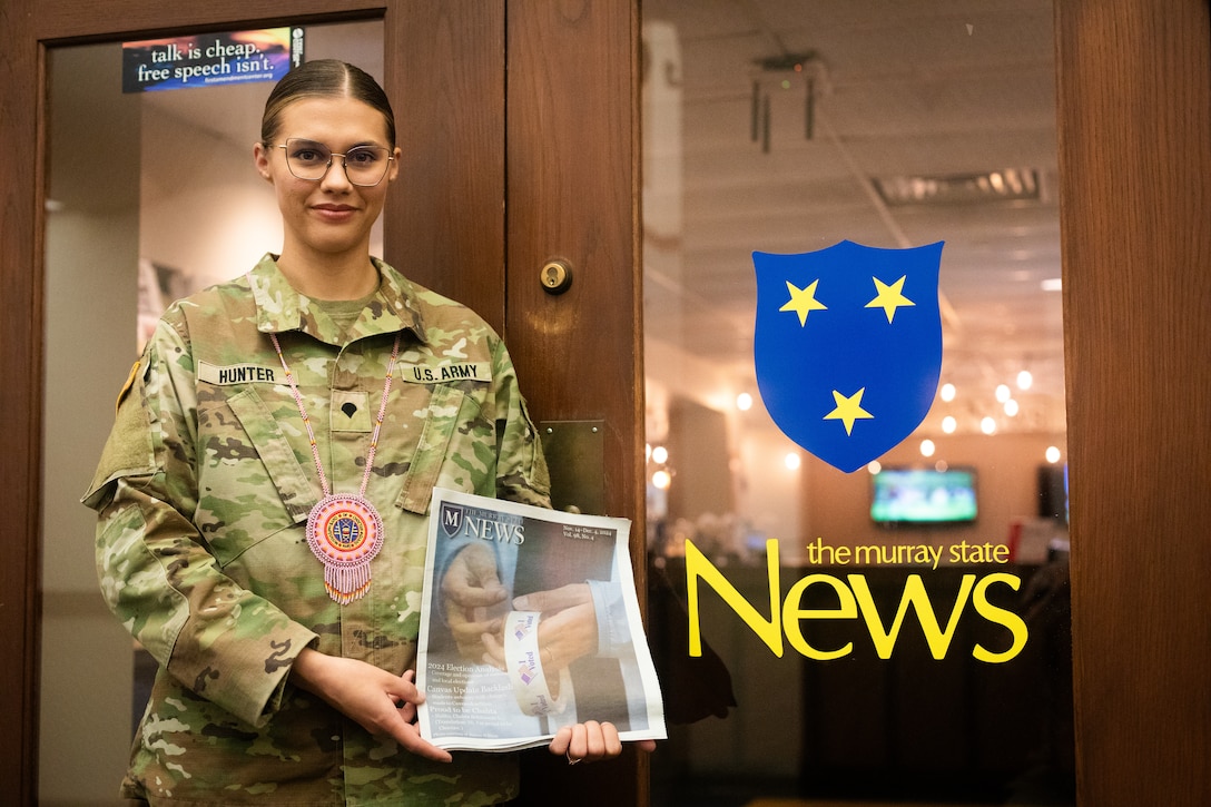 U.S. Army Spc. Brianna Hunter poses in front of the Murray State University newsroom wearing a hand-beaded necklace from the Mississippi Band of Choctaws at Murray State University in Murray, Kentucky on Nov. 25, 2024. Hunter is one-eighth Choctaw, serves in the Kentucky National Guard and is the editor-in-chief for the Murray State University newspaper and has written an article for the newspaper on her Native American Indian heritage. (U.S. Army National Guard photo by Andy Dickson)