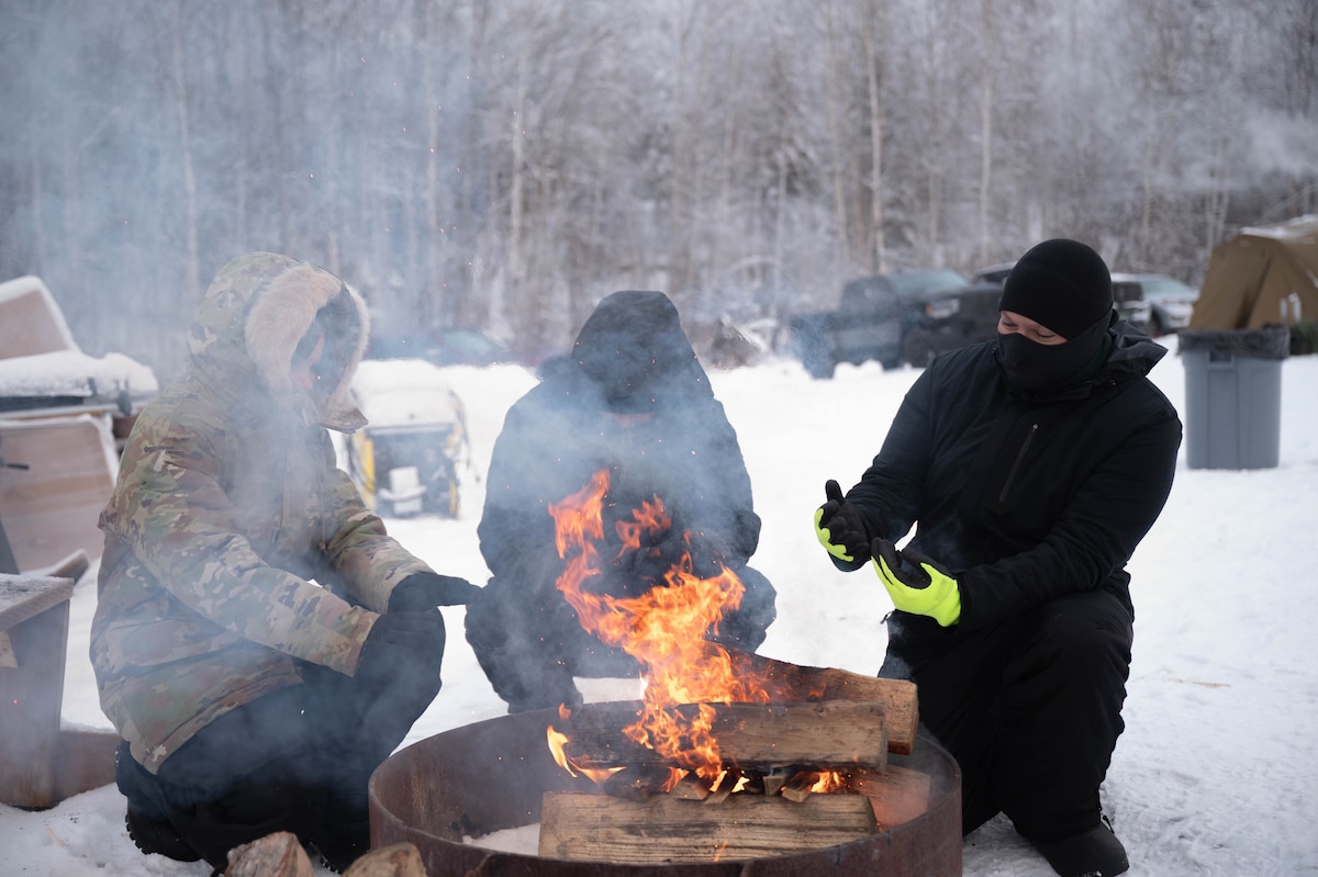 Airmen from the 354th Fighter Wing warm up by a fire during Arctic Resiliency Training at Eielson Air Force Base, Alaska, Nov. 18, 2024.