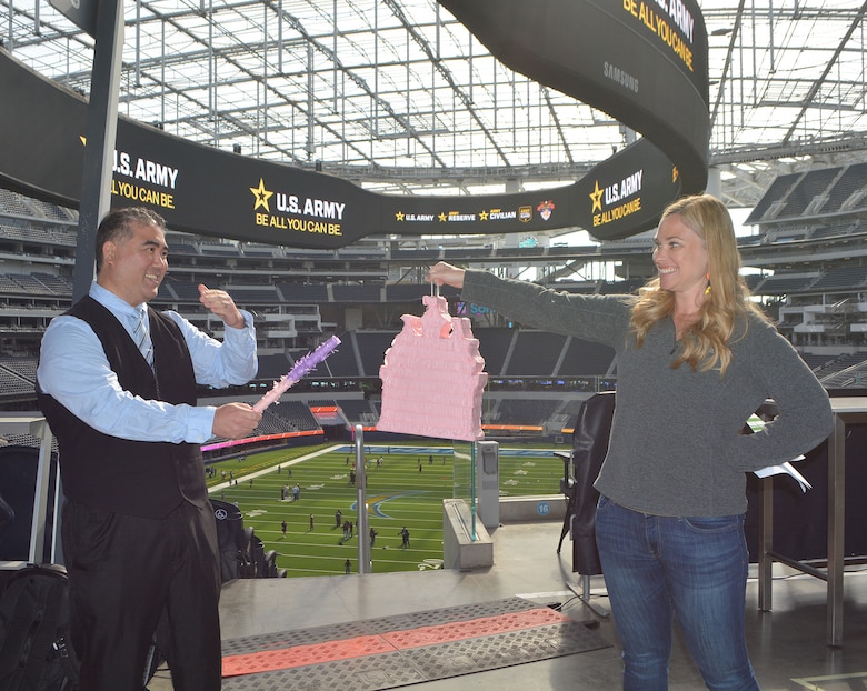 Prospective employee Jinzaemon Kimoto of Los Angeles, left, hits the pinata held by Mary Fronck, contracting chief with the U.S. Army Corps of Engineers San Francisco District, right, after he received an on-the-spot tentative job offer as a contracting specialist with USACE’s Los Angeles District during the Total Army Career Fair Nov. 2 at SoFi Stadium in Inglewood, California. Kimoto was the first of 12 applicants, who received an on-the-spot tentative job offer to work for USACE. The pinata represented an initiation into USACE.