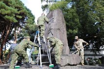 Soldiers assigned to the 765th Transportation (Terminal) Battalion and members of the Japan Ground Self-Defense Force work together to beautify the large “Sobudai” stone monument Nov. 19 on Camp Zama.