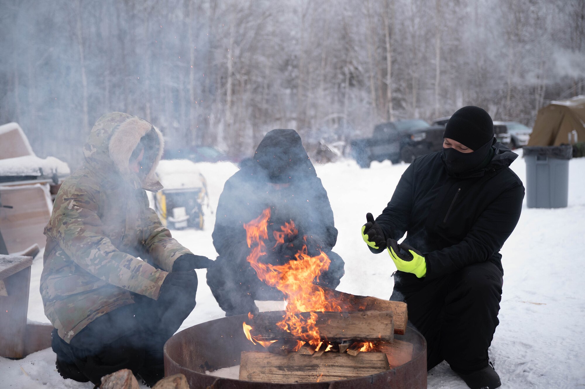 Airmen from the 354th Fighter Wing warm up by a fire during Arctic Resiliency Training at Eielson Air Force Base, Alaska, Nov. 18, 2024.
