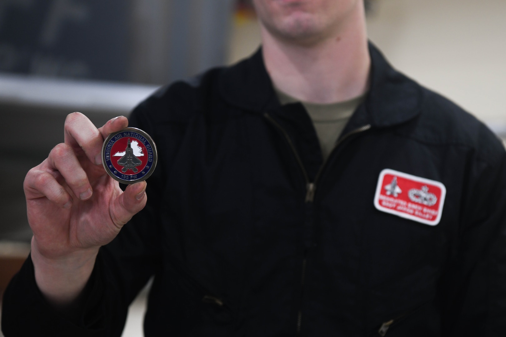 Airman holding up a coin.