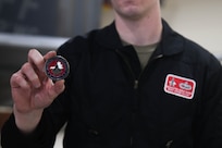 Airman holding up a coin.