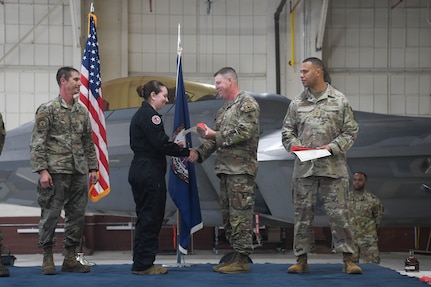 Four Airmen on stage, second from left accepting certificate.