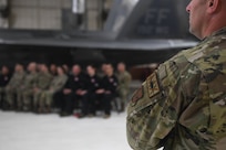 Members sitting in chairs in front of F-22 Raptor